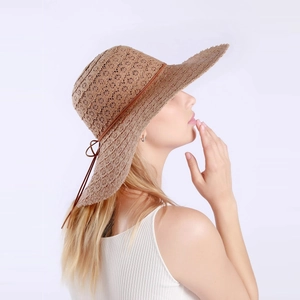 Detail of hollow-weave straw sun hat with brown leather cord and bow on wide brim