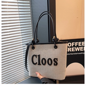 Detailed shot of beige canvas tote bag with black trim and Cloos embroidery branding