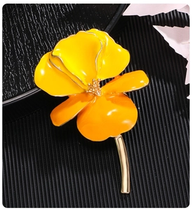Detailed close-up of a vintage iris brooch with yellow enamel petals and golden metal stem