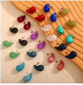 Gros plan de boucles d'oreilles colorées en acier titane sur un plateau en bois