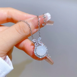 Close-up of titanium steel bow necklace with a white pearl pendant and crystal halo