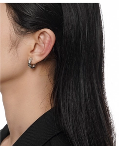 Macro detail of silver ring earrings with irregular hammered texture on model ear