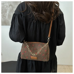 Detail of corduroy crossbody bag with strawberry print and gold flower chain strap