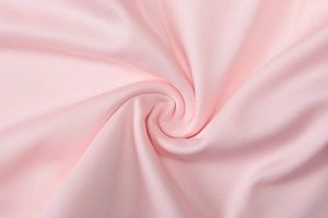 Detailed macro texture of pink knitted fabric showing soft folds and smooth material