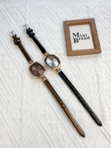 Detail of vintage oval quartz watches with brown and black leather straps on white fabric