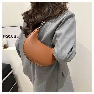 Brown faux leather crescent underarm bag shown on model wearing grey suit jacket