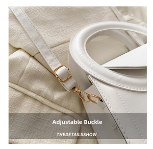 Detailed view of the white handbag showing the gold metal buckle and leather stitching