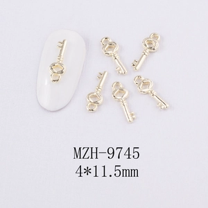 Vue macro d'une mini décoration d'ongles en alliage doré, forme clé, 4x11,5mm