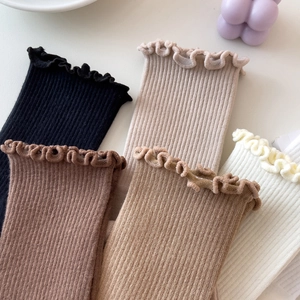 Close-up of ruffled edges on cotton knit socks in neutral tones like beige and black