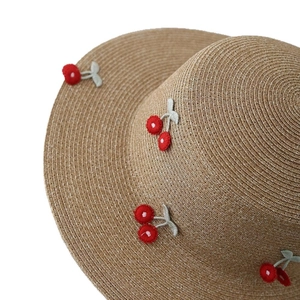 Straw sun hat for women with embroidered red cherry patterns on a woven texture