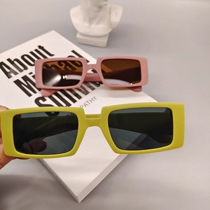 Détail de lunettes de soleil carrées vert fluo et rose poudré avec monture épaisse en acétate