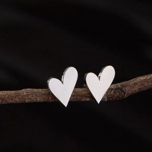 Boucles d'oreilles cœur argentées minimalistes sur fond de branche rustique