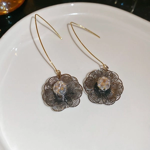 Détail de boucles d'oreilles fleur plaquées or 18K avec zircon sur plateau céramique