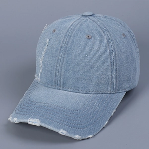 Close-up of distressed denim baseball cap with frayed holes and vintage texture details