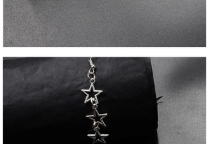 Macro shot of silver hollow star earrings hanging on a display stand showing metal texture