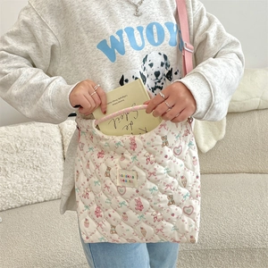 Détail du sac cabas matelassé avec bandoulière rose porté par un mannequin dans un intérieur