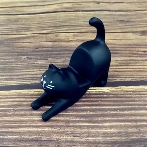 Detail of creative black resin stretching cat miniature with phone holder slot feature