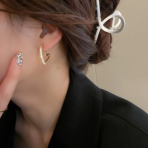 Gros plan de la boucle d'oreille cœur dorée avec cristaux de zircone sur un modèle