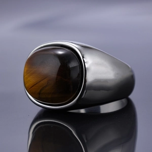 Polished stainless steel ring for men featuring an oval tiger eye stone on black surface