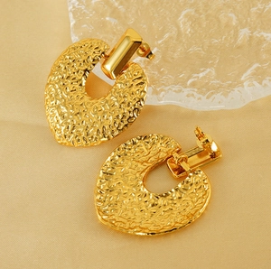 Détails macro de boucles d'oreilles dorées avec texture de surface martelée vintage