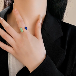 Close-up of a model wearing a gold adjustable ring with blue and green gemstones