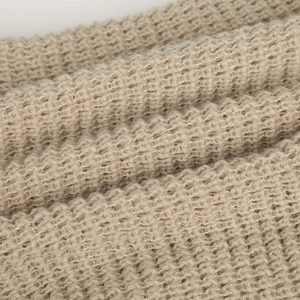 Dettaglio della trama a maglia beige di un caldo berretto invernale da donna