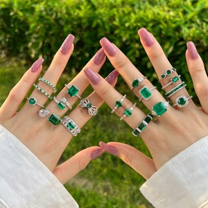 Detailed view of silver rings featuring square emerald cut and pear shaped green gemstones