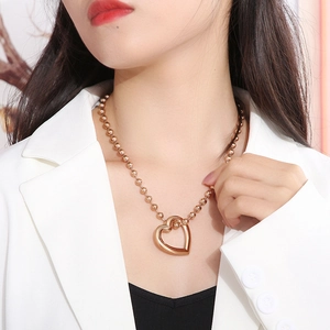 Close-up of rose gold hollow heart pendant with elegant bead chain on model