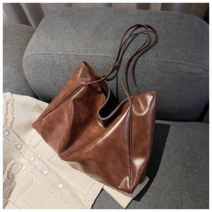 Close-up of retro brown leather tote bag with fine stitching on a grey sofa