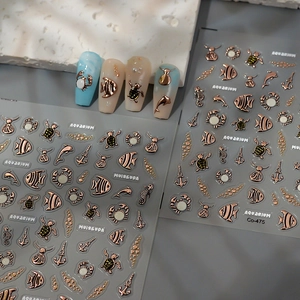 Détail macro de stickers ongles 3D or rose avec motifs marins en relief gaufré