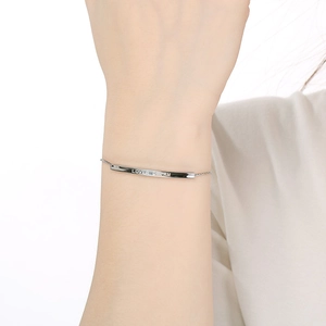 Macro shot of silver bar bracelet engraved with LOVER DREAM on female wrist