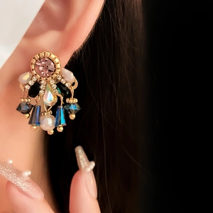 Detail of vintage gold pearl tassel earrings with colorful rhinestones on a female model