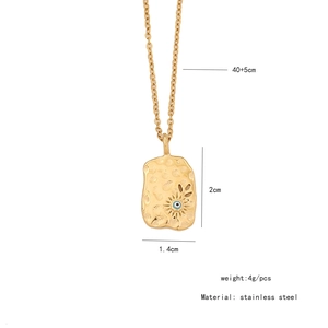 Macro detail of gold stainless steel heart pendant with evil eye and leaf engraving