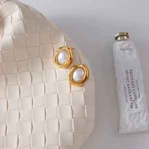 Elegant 18K gold-plated irregular wavy earrings with resin pearls on a white bag