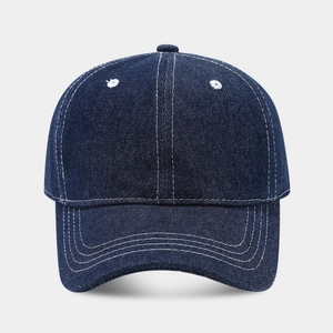 Detail of dark blue denim baseball cap with contrast white stitching and curved brim