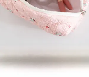 Detailed view of pink quilted makeup bag with heart and rabbit prints and white zipper