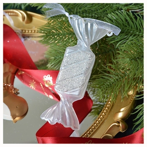 Dettaglio dell'ornamento a forma di caramella trasparente con glitter argento e nastro