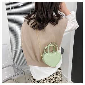 Detail of light green heart-shaped mini jelly bag worn with gold chain strap