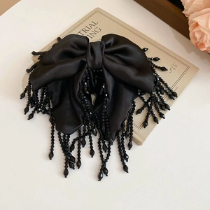 Détail de la pince à cheveux noeud en satin noir avec pampilles de perles de luxe