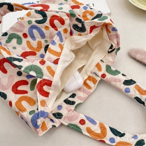 Détail d'un sac cabas crème matelassé avec motifs colorés et rangement intérieur
