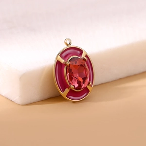 Macro view of oval red gemstone pendant with gold metal frame and enamel detail