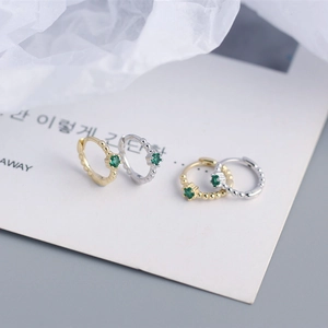 Macro view of gold and silver S925 beaded earrings set with emerald green zircon stones