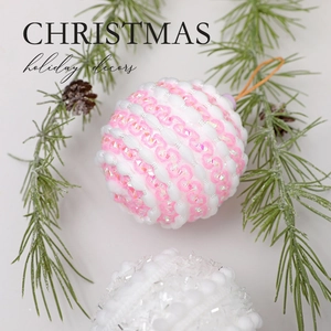 Pink and white spiral Christmas ball ornaments decorated with sparkles on pine branches