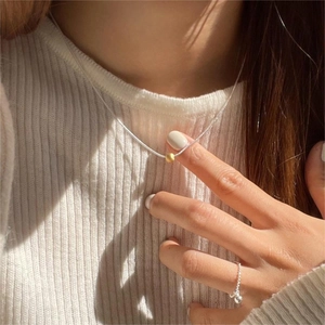 Close-up of a 925 sterling silver ball snake chain necklace on a model with warm lighting