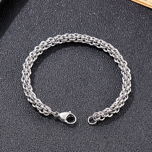 Detailed view of silver stainless steel braided chain bracelet with lobster clasp closure