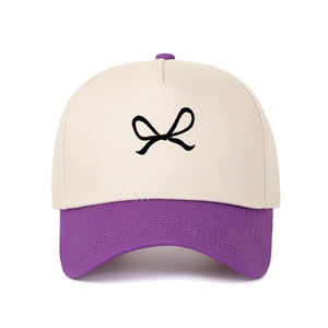 Detail of a color-block baseball cap featuring a bow pattern and contrast purple brim