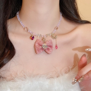 Close-up of pink fabric bow necklace with heart and crescent moon charms on a model