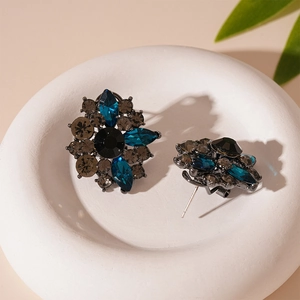Macro shot of vintage floral stud earrings with deep blue crystals on a white pedestal