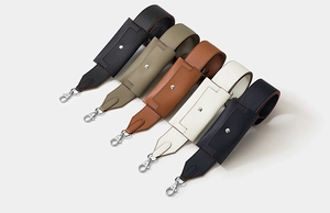 Detail of wide leather shoulder straps with litchi texture and silver metal spring buckles
