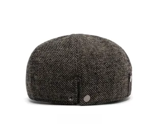 Rear view of herringbone tweed flat cap showing metallic snap button and leather strap